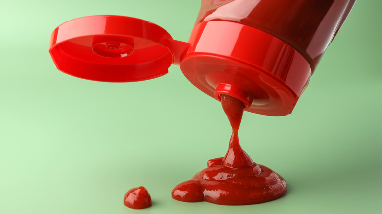 Unlabeled bottle of ketchup squeezing out a bit of the condiment