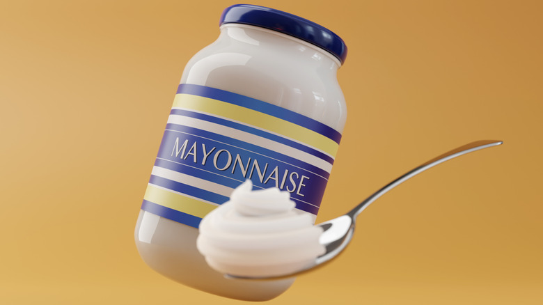 Jar of mayonnaise behind a spoonful of the condiment