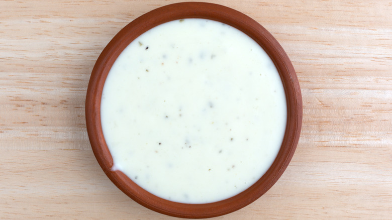 Brown ramekin of ranch dressing on table