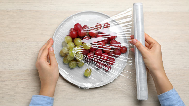 Hands storing grapes on plate