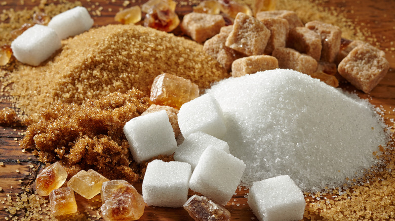 An assortment of different kinds of sugar in a pile on a wooden surface