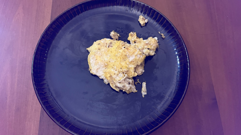 Eggs scrambled in butter on a blue plate sitting on a wooden table