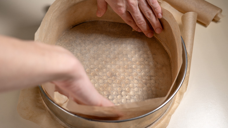 Cake pan being lined with a parchment collar.