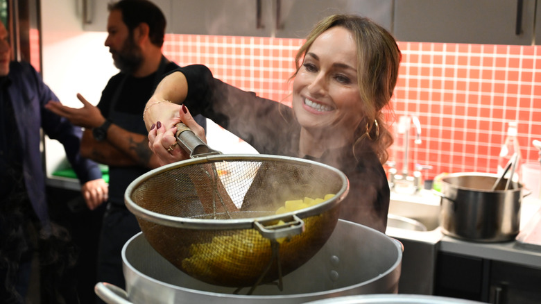 Giada De Laurentiis straining a bowl of pasta in a kitchen