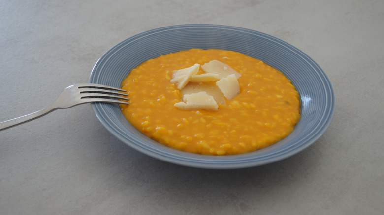 Risotto and parmesan cheese on a blue plate with a fork