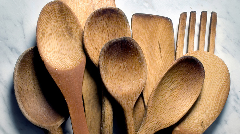 several used wooden spoons and spatulas over marble background