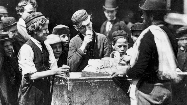 Black and white photo of kids gathered around ice cream vendor