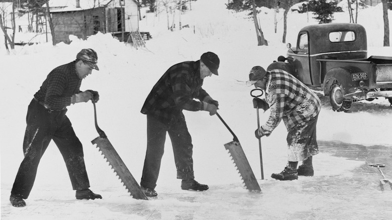 Men use saws to cut through ice for harvest