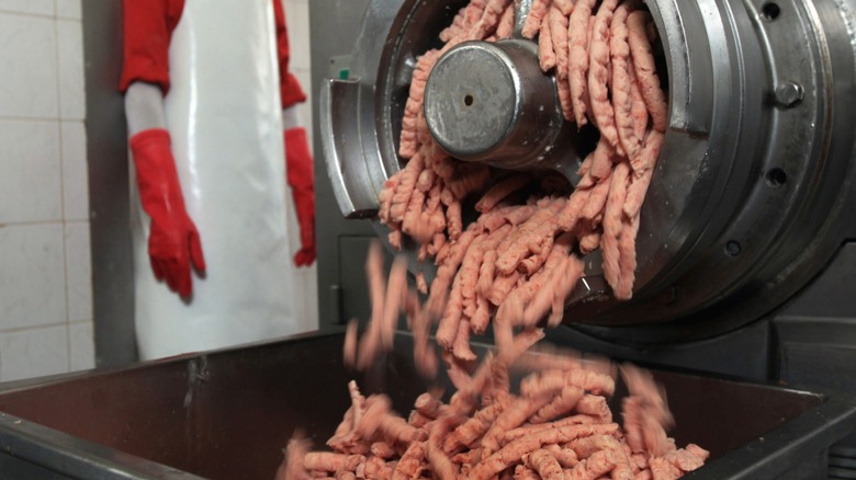 Meat coming out of an enormous industrial grinder.