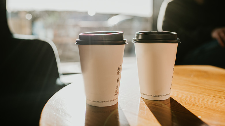 Two paper coffee cups on table