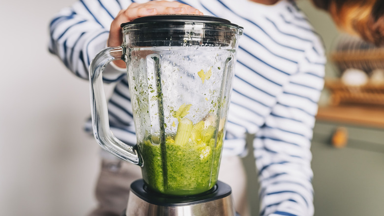 Blender with green smoothie inside