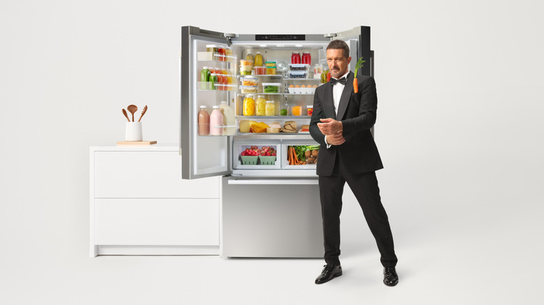 Antonio Banderas in a suit in front of a stocked refrigerator