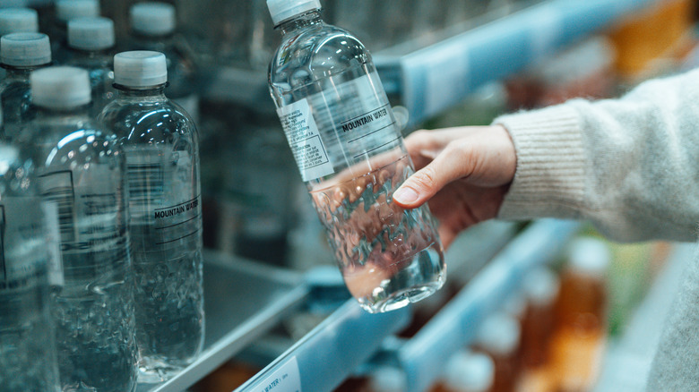 Customer taking a water bottle off a store shelf