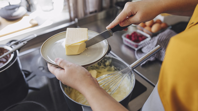 Person adding butter to dough