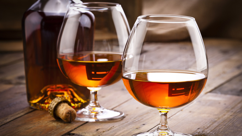 Two glasses of Cognac and a bottle on a wooden table