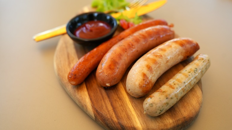 Multiple sausages on wooden board including hot dog and bratwurst