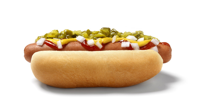 Hot dog in bun with ketchup, mustard, onions and relish