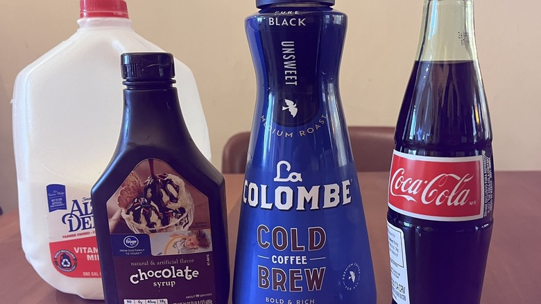 Ingredients for mocha cola: milk, chocolate syrup, cold brew, and Coke