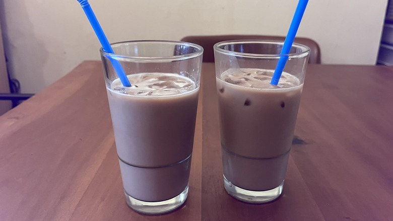 Two glasses of mocha cola with blue straws on wooden table