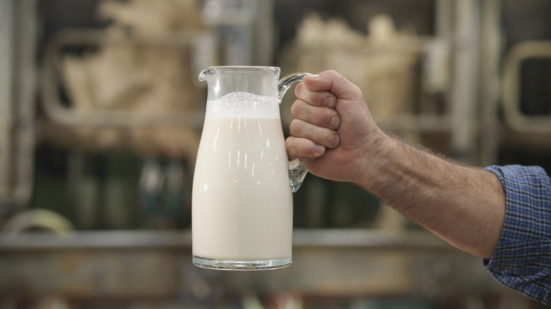 man's hand holding jug of milk