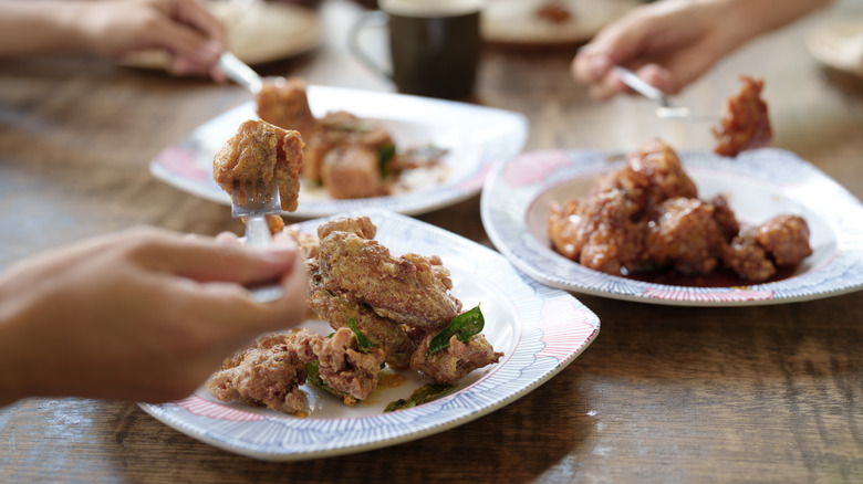 People eating different types of chicken on white plates