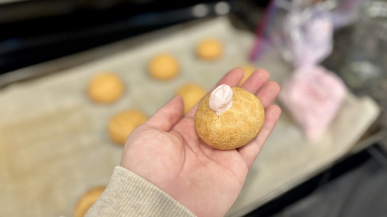 holding a creme puff with creme inside