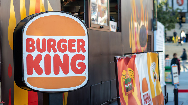 A vintage-styled Burger King logo, with red text saying "Burger King" stacked between two brown buns, like a burger