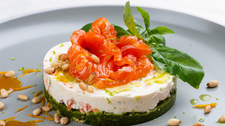 savory cheesecake topped with smoked salmon and fresh basil on a grey plate