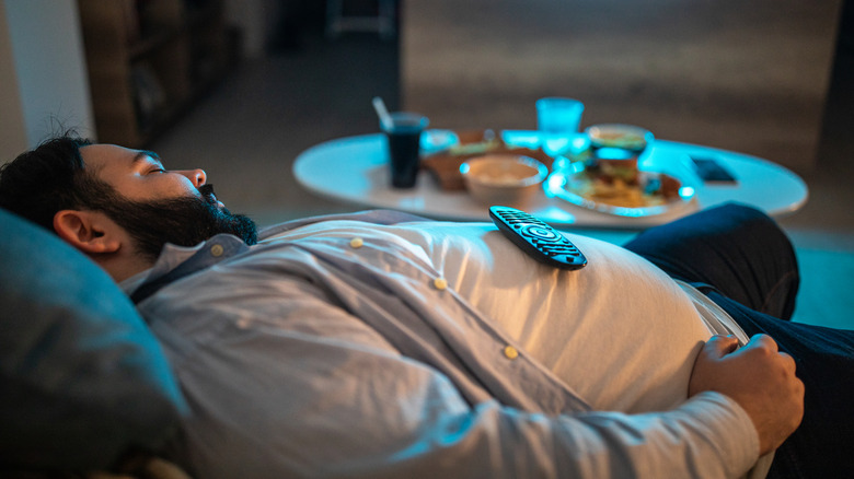 A man sleeps next to a table laden with food