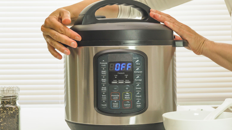 An instant pot with a person twisting the lid to remove it