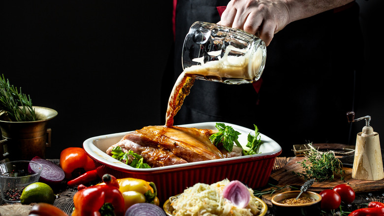 Pouring beer into pan of marinating pork roast