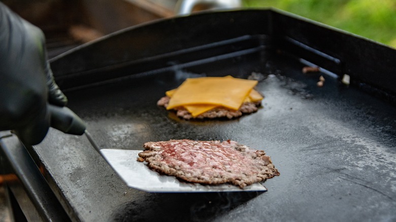 Smashed burger patty is scraped off the grill