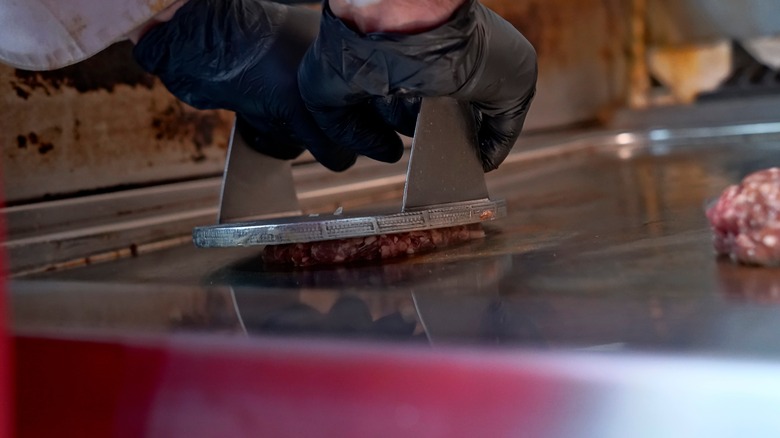 A press is used to smash a burger patty down