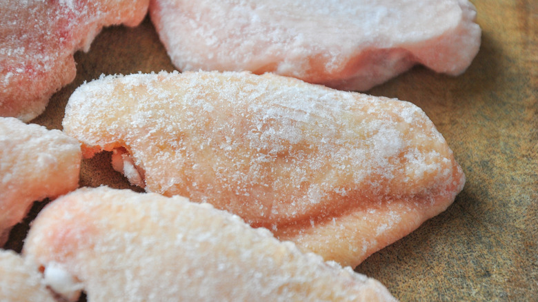 Frozen, raw chicken wings on a cutting board