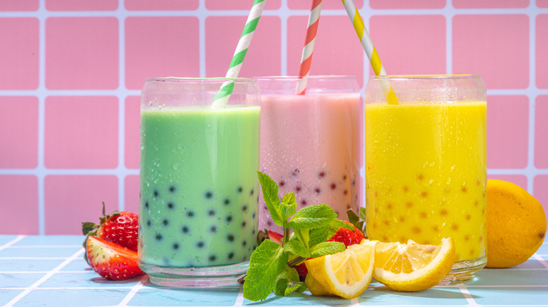 Three glasses of pastel bubble tea on a pink and blue tiled surface