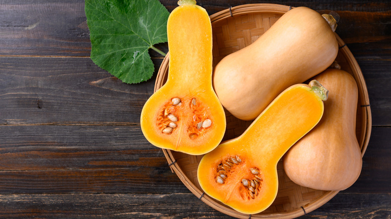 Two whole butternut squashes and one halved butternut squash in a basket