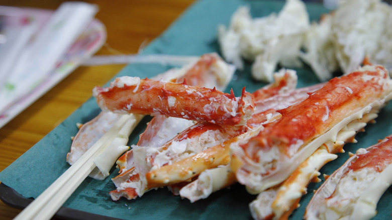 Crab legs and chopsticks on a blue board