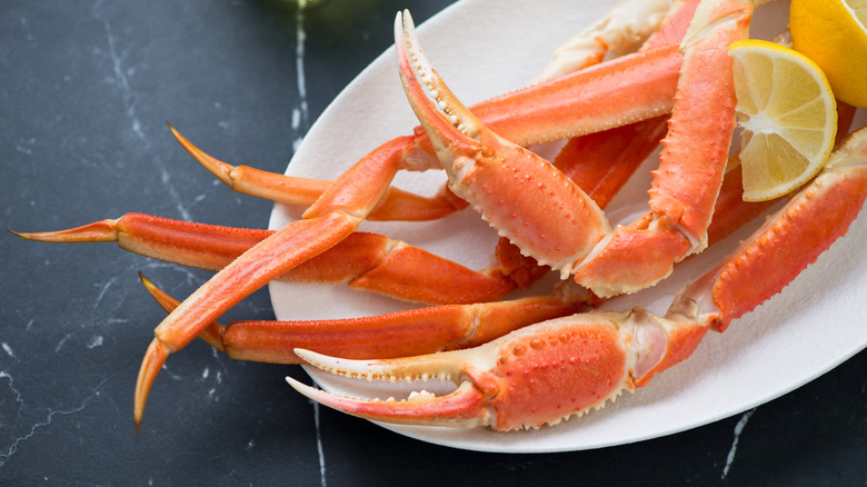 Snow crab legs arranged with lemon wedges on a white plate