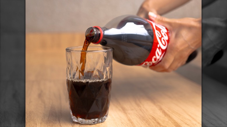 hand pouring Coke into glass