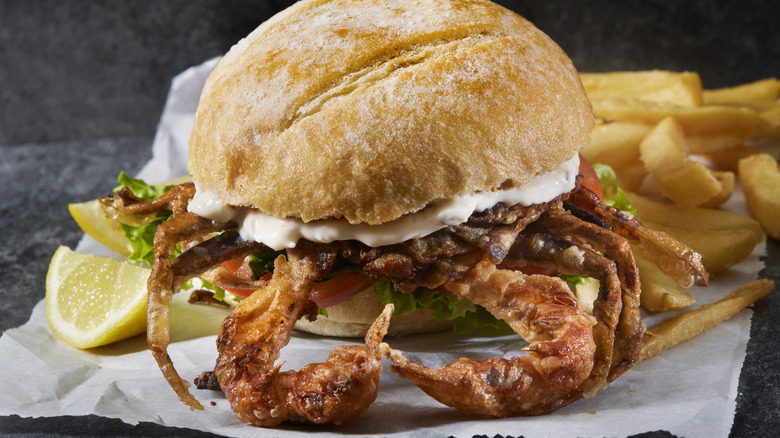 A whole deep fried soft shell crab on a roll with mayonnaise