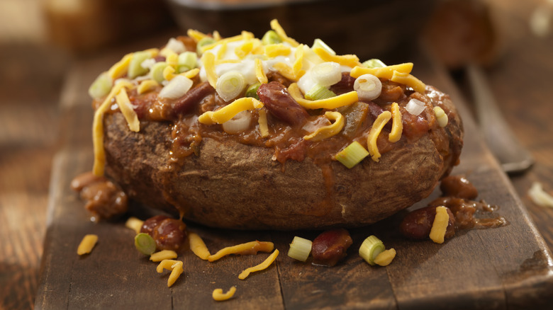 baked potato with chili on cutting board