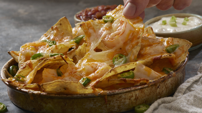 a tray full of nachos with jalapenos under melty cheese