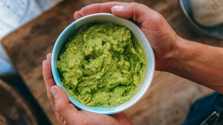 hands holding guacamole bowl