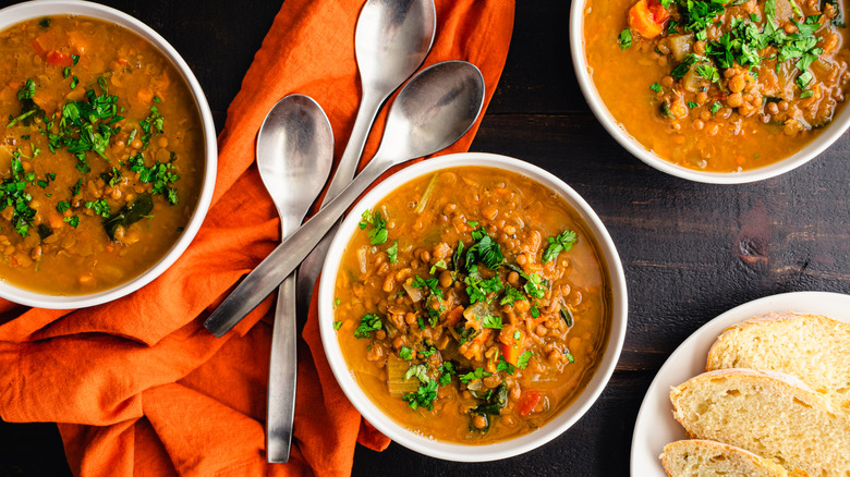 Three bowls of lentil soup and plate of bread