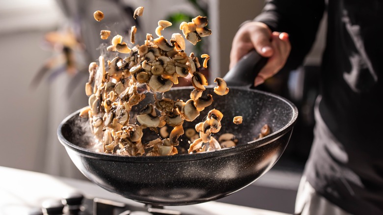 sliced mushrooms lifted in the air from a pan