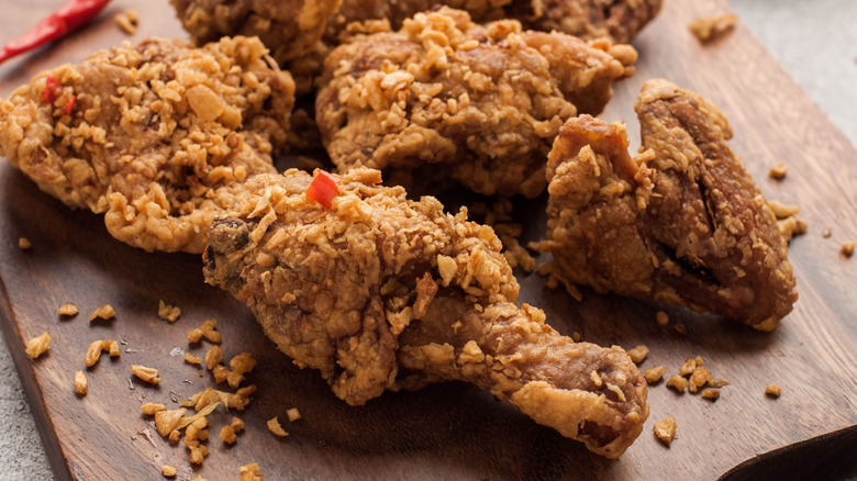 Pieces of fried chicken sitting on a cutting board.