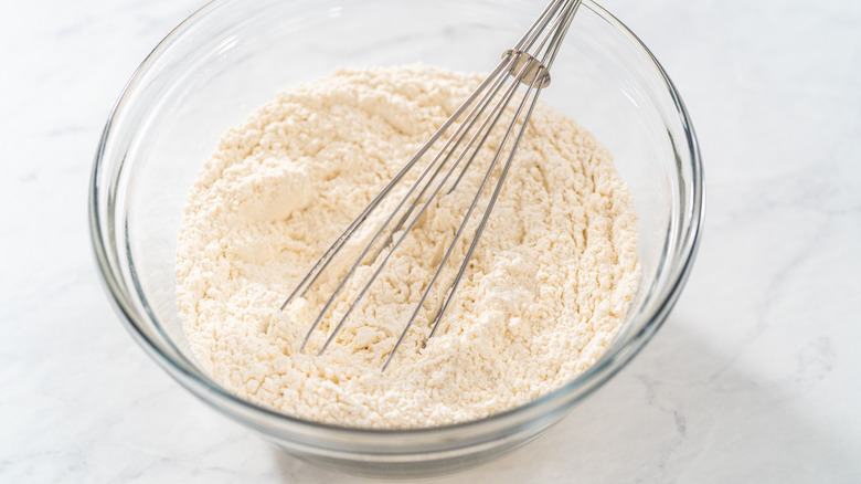 Dry ingredients in a glass bowl with a whisk in it