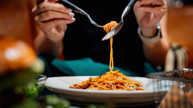 woman scooping up pasta at a restaurant