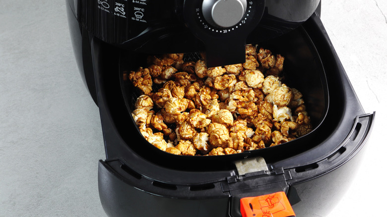 air fryer basket with popcorn in it