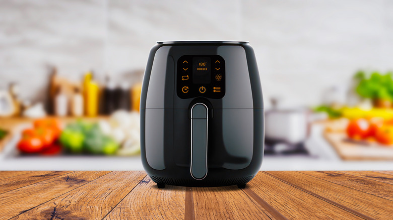 An air fryer on top of a wooden table in the kitchen